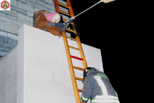 Immagine Befana con pompiere sopra palazzo terragni